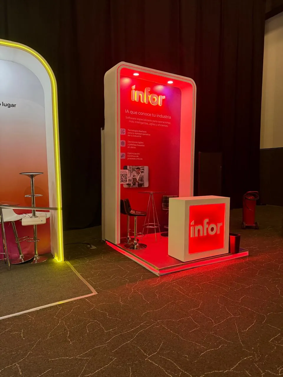 Stand rojo de infor con el claim «IA que conoce tu industria» y tres bullets de beneficios.