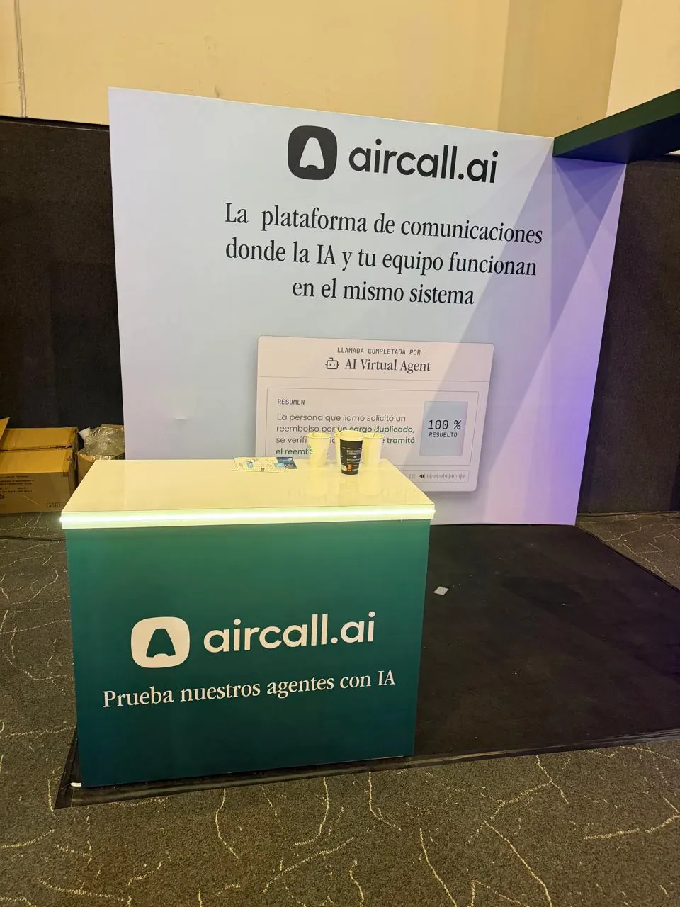 Stand verde de aircall.ai con una tarjeta de demostración que muestra una llamada resuelta por un agente virtual al 100%.