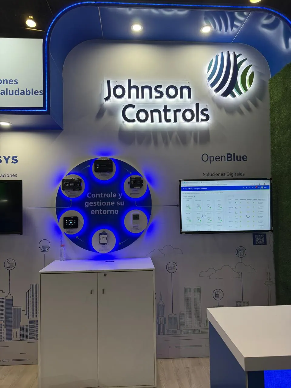 Stand de Johnson Controls con la marca OpenBlue y un anillo iluminado de dispositivos de control de edificios.